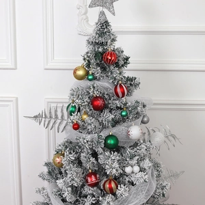 Flocked Christmas tree with colorful hanging ornaments and tree topper decoration