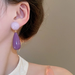 Close-up of model wearing purple acrylic teardrop earrings with silver needle posts