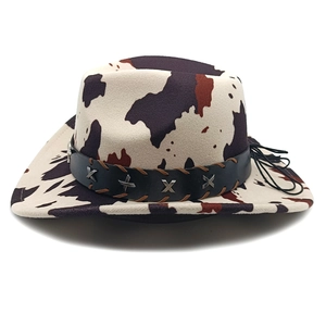 Detail of cow print cowboy hat featuring black leather braided band with silver X-shaped accents
