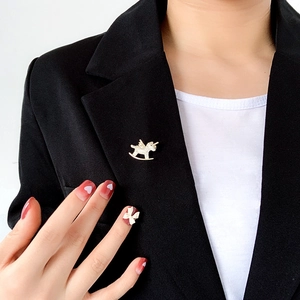 Close-up of a gold unicorn brooch with sparkling rhinestones on a black blazer jacket
