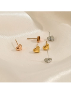 Vue détaillée de clous d'oreilles en forme de cœur en or, argent et or rose sur soie