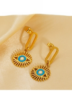 Detailed view of titanium steel gold evil eye earrings on champagne silk fabric