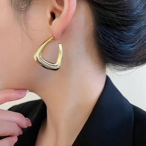Close-up of golden geometric triangle stud earrings with polished mirror finish for women