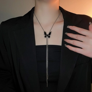Silver butterfly necklace with black pendant and tassels worn on a model in a suit