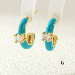 Macro shot of C-shaped blue enamel gold earrings with a sparkling round zircon stone