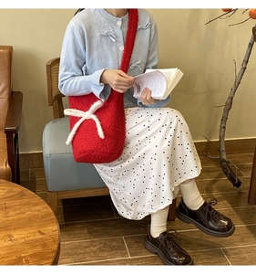 Detailed plush red bucket bag featuring a soft white bow and cozy fleece texture