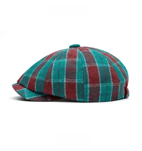 Side view of red and green plaid newsboy cap in thick wool fabric with short brim