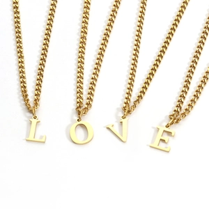 Detail view of 18K gold-plated stainless steel LOVE letter pendant necklaces in a flat lay