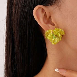Dettaglio di modella che indossa orecchini a fiore con perline verdi e design a foglia