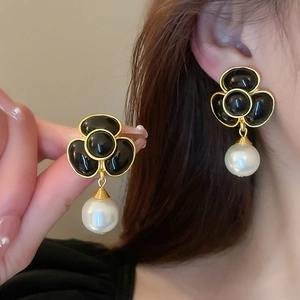 Detail of vintage gold clover earrings with black stones and white pearl drops