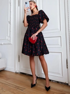 Detail of square neck dress with cherry print, puff sleeves and a red heart clutch