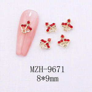 Macro shot of 8x9mm gold nail art charm with red rhinestones and bell design