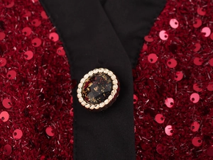 Dettaglio del bottone dorato glitterato su giacca in tweed rosso con paillettes