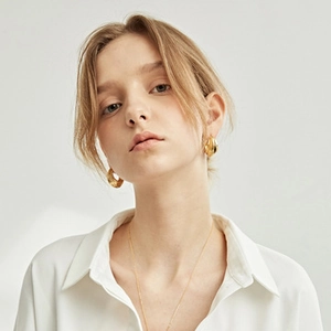 Close-up of elegant gold plated flower earrings worn with matching necklace on a model