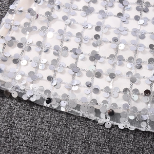 Gros plan de paillettes argentées sur tissu résille blanc montrant les détails