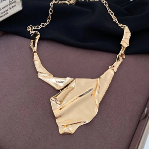 Close-up of golden irregular wrinkled metal pendant with liquid style art finish
