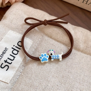 Detail of a brown elastic hair tie with blue cat paw and puppy cartoon pendant