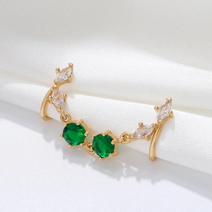 Detailed view of a gold U-shaped nose clip with green zircons on white silk background