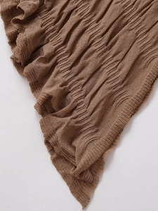 Detailed macro view of brown pleated knit mesh fabric with vertical textured patterns
