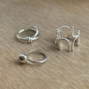 Detailed view of S925 sterling silver minimalist U-shaped rings on a light wood surface