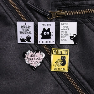 Détail de cinq broches chat tarot en émail fixées sur une veste en cuir noir