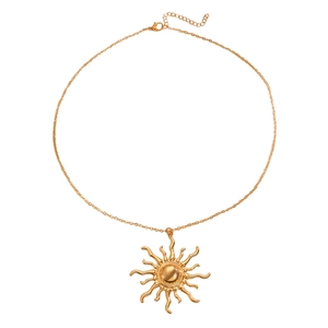 Macro detail of a golden sun pendant necklace with radiant flame texture and metal ball center