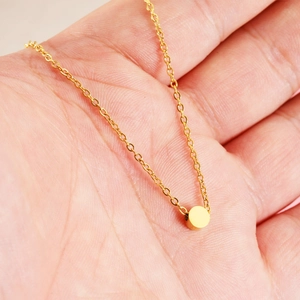 Collana dorata con ciondolo a sfera da 5mm e catena sottile nella mano