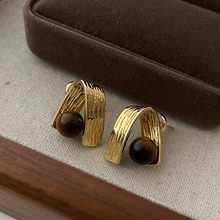 Close-up of vintage gold U-shaped earrings with dark brown spherical natural stones