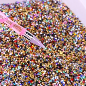 Gros plan d'un stylo de nail art saisissant un strass vert avec précision