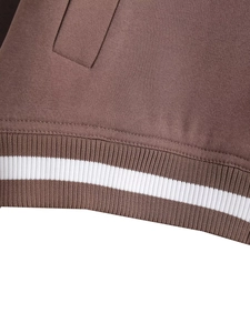 Detailed close-up of brown ribbed cuffs with dual white stripes on the baseball jacket