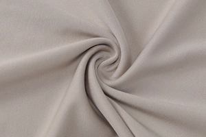 Macro texture of light grey knitted fabric with elegant spiral folds and soft drape finish