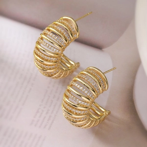 18K gold plated C-shaped earrings with layered zircon pavé on magazine background