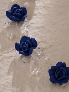 Detail view of handcrafted deep blue ceramic roses with pearls on silver bridal headband