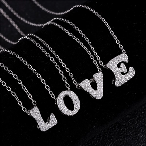 Macro shot of micro-pave zircon LOVE letter pendants on silver tone link chains