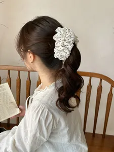 Polka dot ruffled scrunchie hair accessory shown on a model high ponytail hairstyle