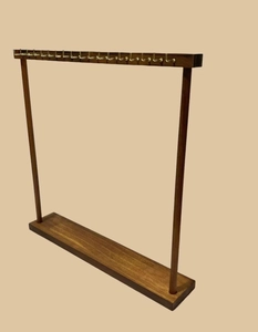 Detailed view of dark brown wooden necklace display rack with vintage brass hooks