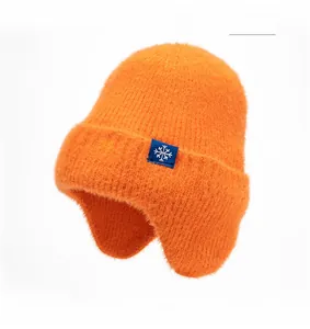 Détail du bonnet d'hiver orange montrant la texture polaire et l'écusson flocon bleu