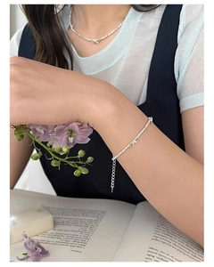 Bracciale e collana con fiocco in argento esposti su un libro antico con fiori color viola