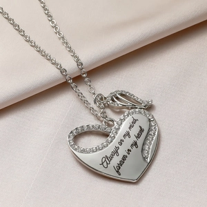 Detailed view of silver heart and wing pendant engraved with Always on my mind text