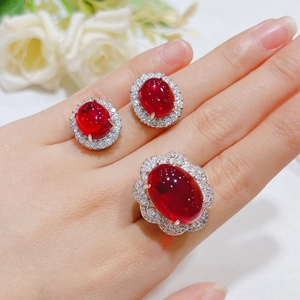Detail of red gemstone jewelry set including oval ruby stud earrings and ring on a model