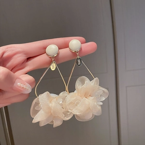 Close-up of elegant oversized apricot fabric flower drop earrings with golden frames