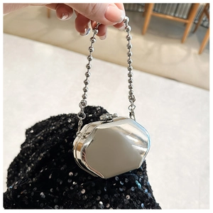 Close-up of hexagonal silver metal mini bag with mirror finish and pearl chain handle