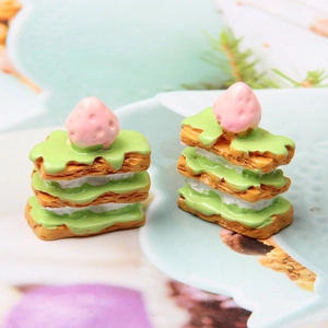 Close-up of two miniature resin strawberry napoleon cakes with green cream for DIY crafts