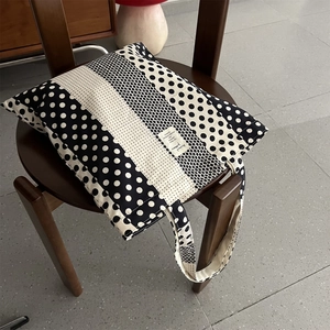 Dettaglio ravvicinato di una borsa in tela a pois e strisce bianche e nere su una sedia