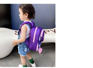 Toddler rocket backpack in purple with white stars pattern and side pocket on child