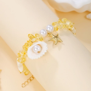 Detail of seashell and starfish charms on a bohemian beaded bracelet with yellow stones