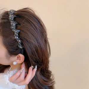 Detailed view of an elegant wavy headband with sparkling rhinestones on brown hair