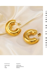 Detailed view of polished 18K gold-plated C-shaped chunky earrings on white silk fabric