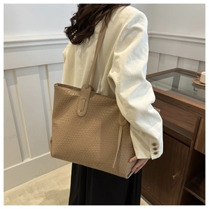 Détail du grand sac cabas tissé kaki porté par un mannequin pour un usage quotidien
