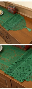 Close-up of green lace table runner with intricate hollow patterns and elegant tassels